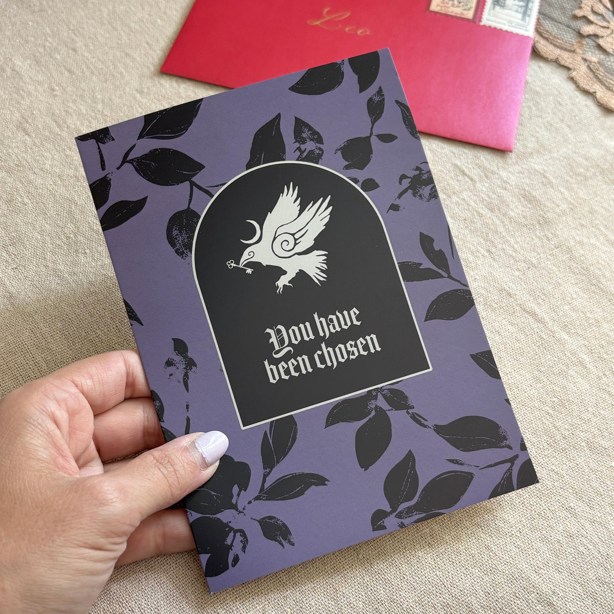 A black and purple patterned greeting card with an illustration of a crow and the text "You have been chosen"