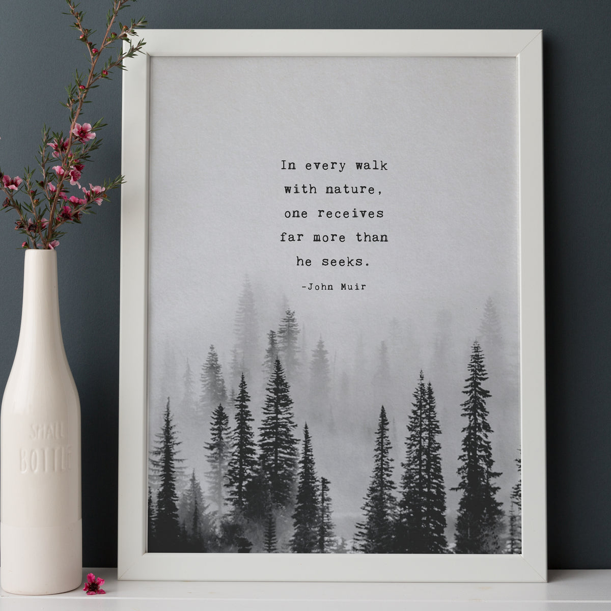 An Art print of misty black and white pine trees and the quote by John Muir which says "In every walk with nature, one receives far more than he seeks"