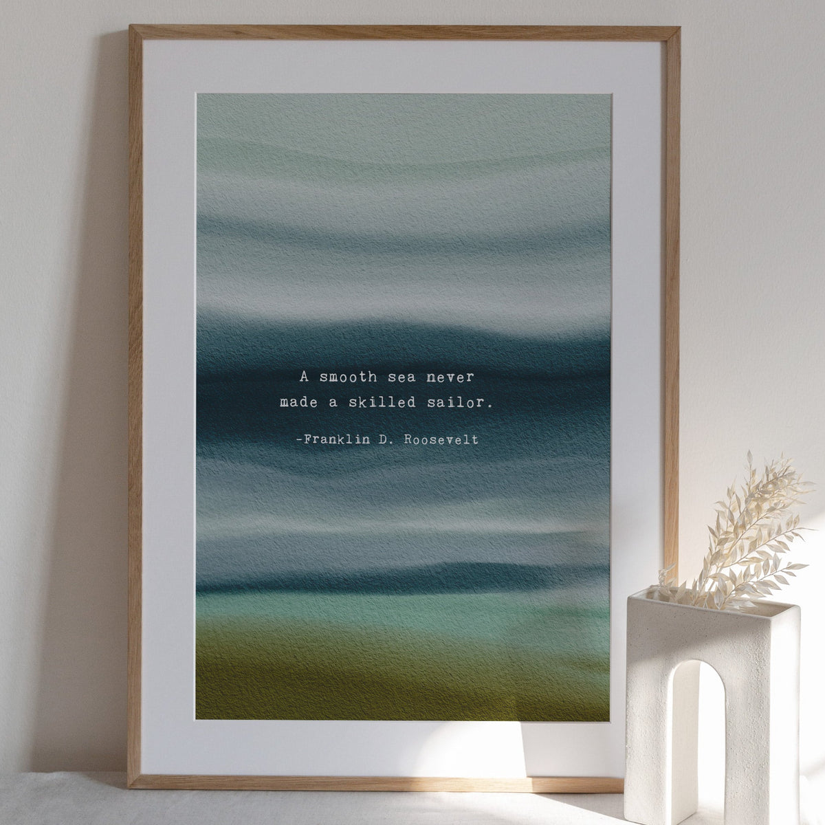A vertical art print featuring an abstract watercolor seascape in muted teal, blue, and olive tones, with a white typewriter-style quote in the center reading, 'A smooth sea never made a skilled sailor. -Franklin D.