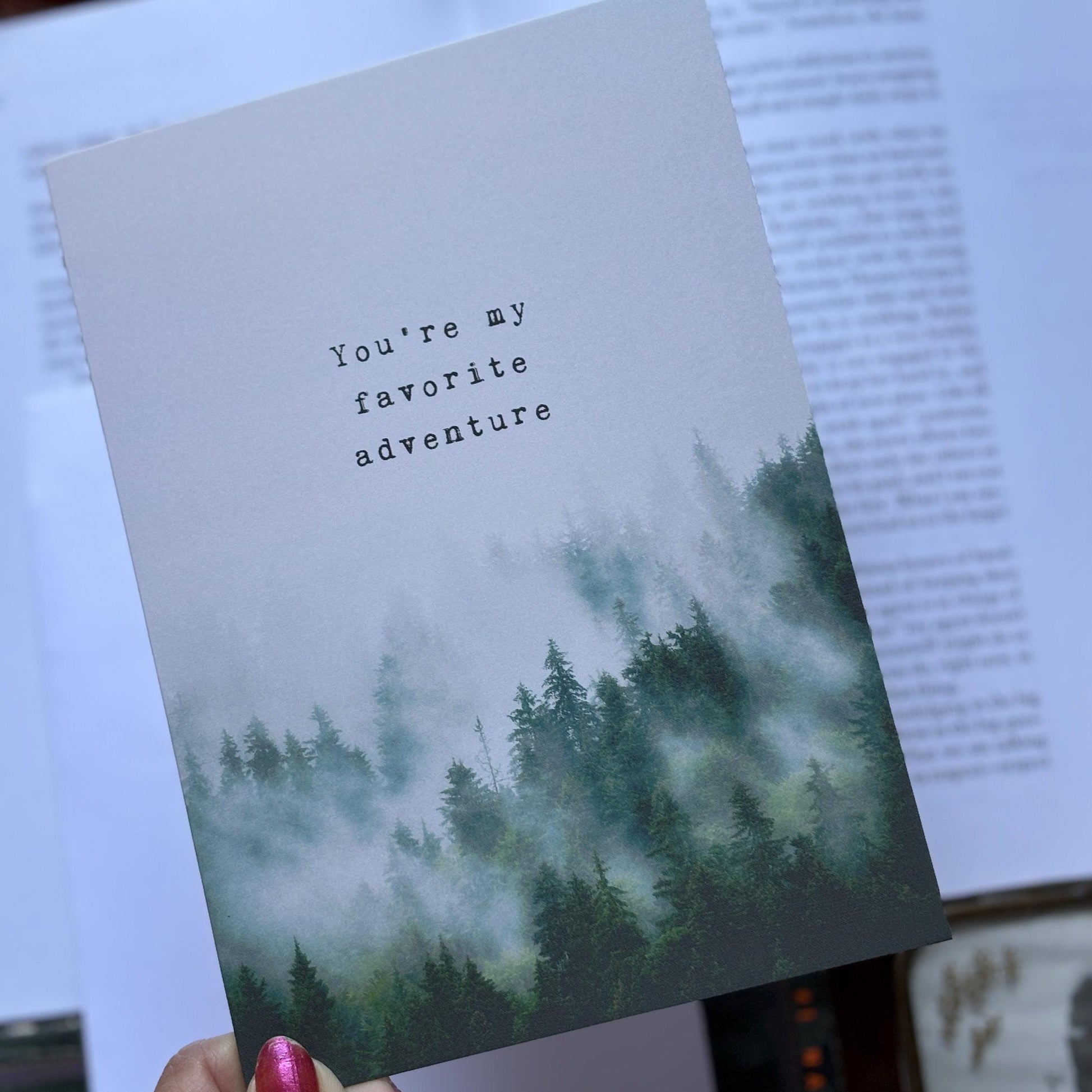 Greeting card featuring a misty pine forest and the text 'You're my favorite adventure'. 