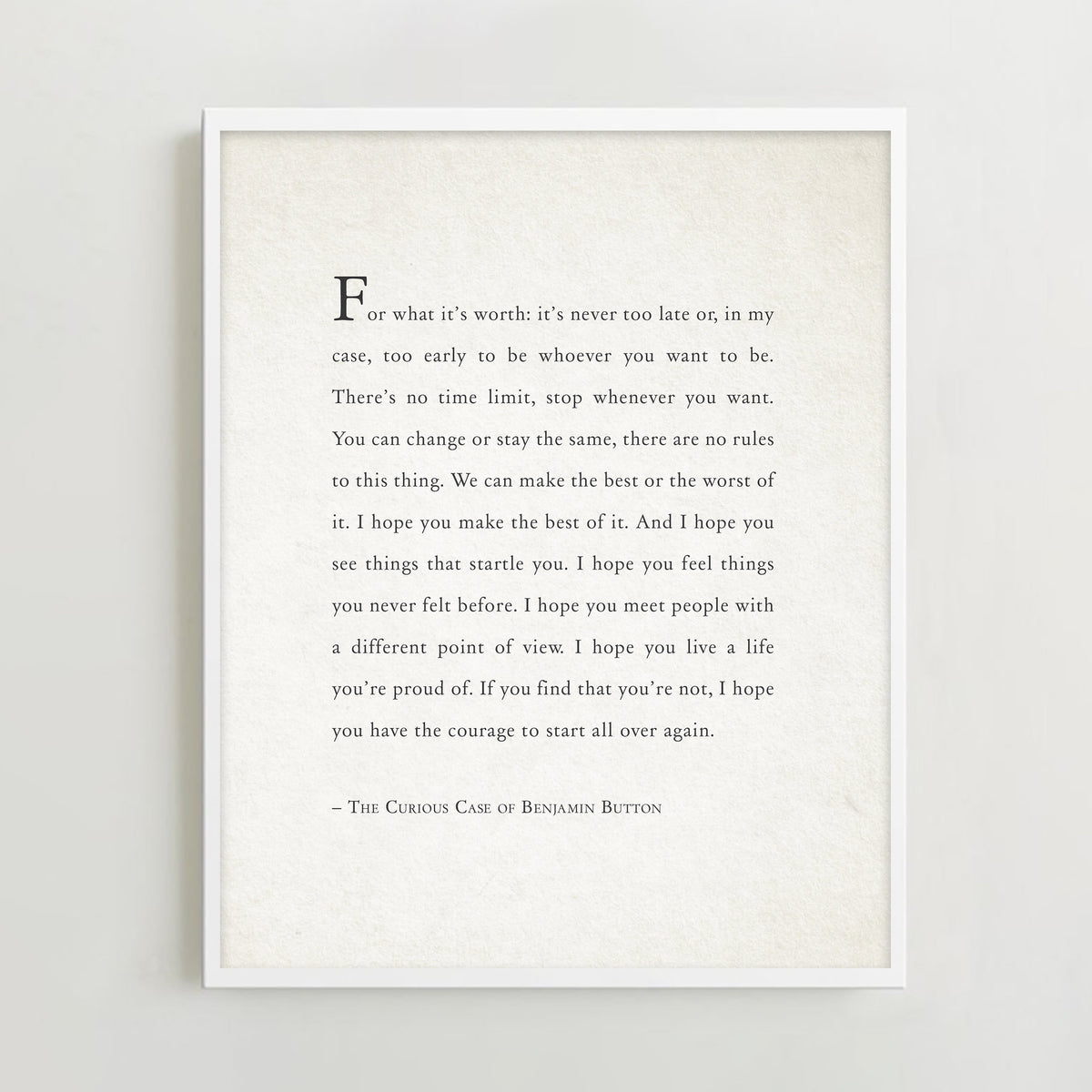 A framed typographic art print featuring a quote from The Curious Case of Benjamin Button in black serif text on an off-white background. It says "for what it's worth: it's never too late or, in my case, too early to be whoever you want to be."