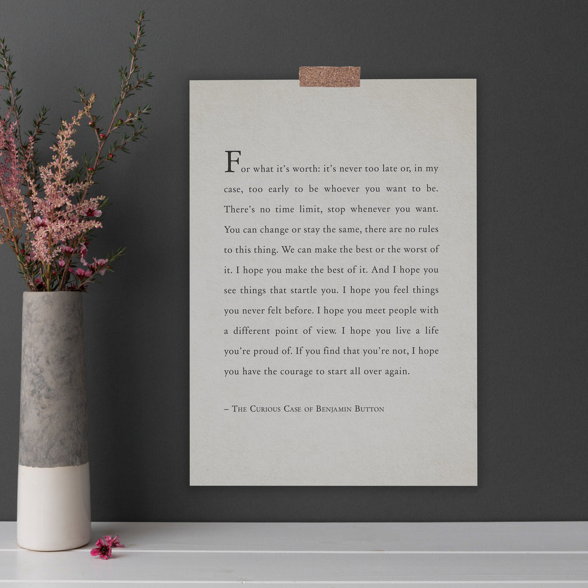 A framed typographic art print featuring a quote from The Curious Case of Benjamin Button in black serif text on an off-white background. It says "for what it's worth: it's never too late or, in my case, too early to be whoever you want to be."