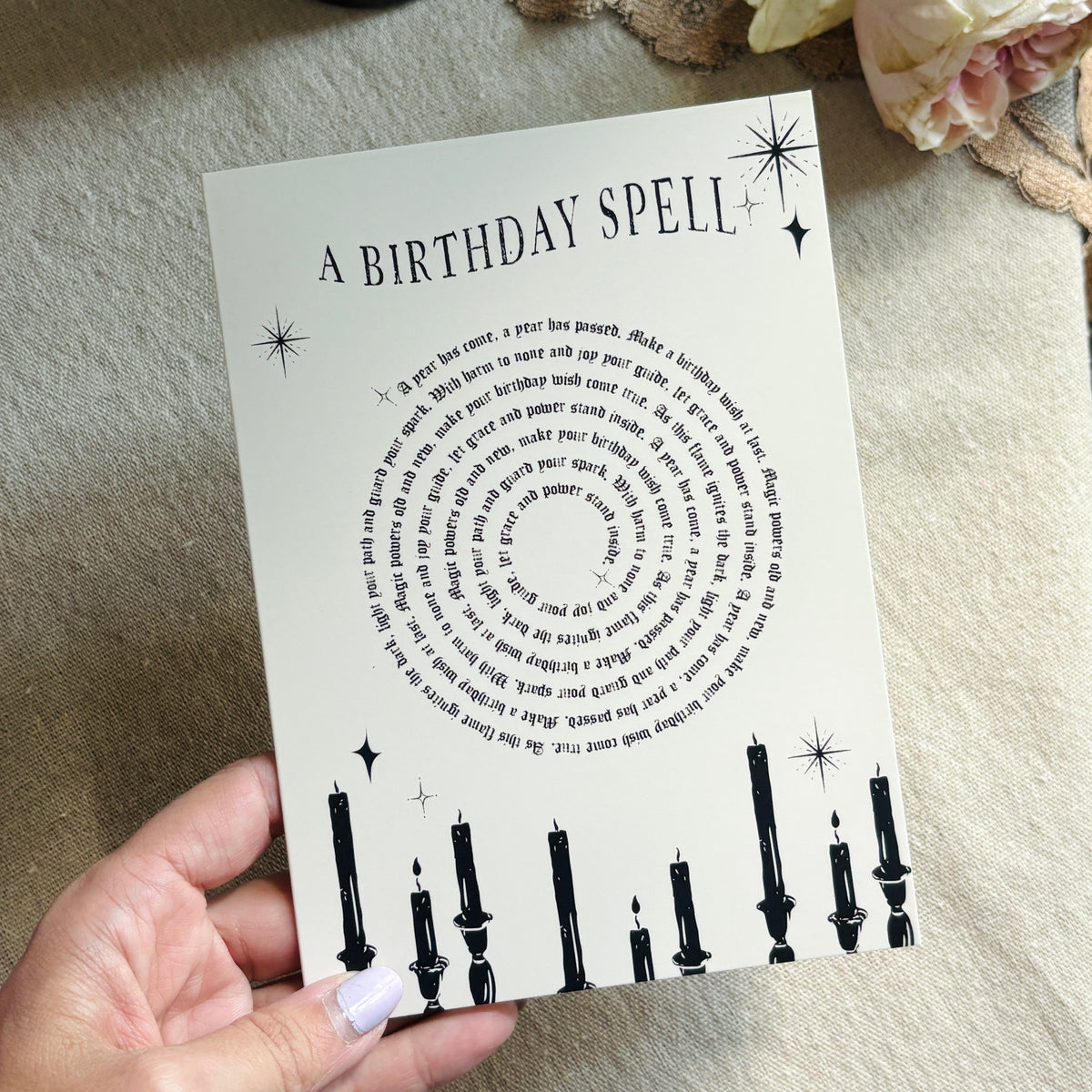 A greeting card that says "a birthday spell" with text for the spell in a spiral above black candles