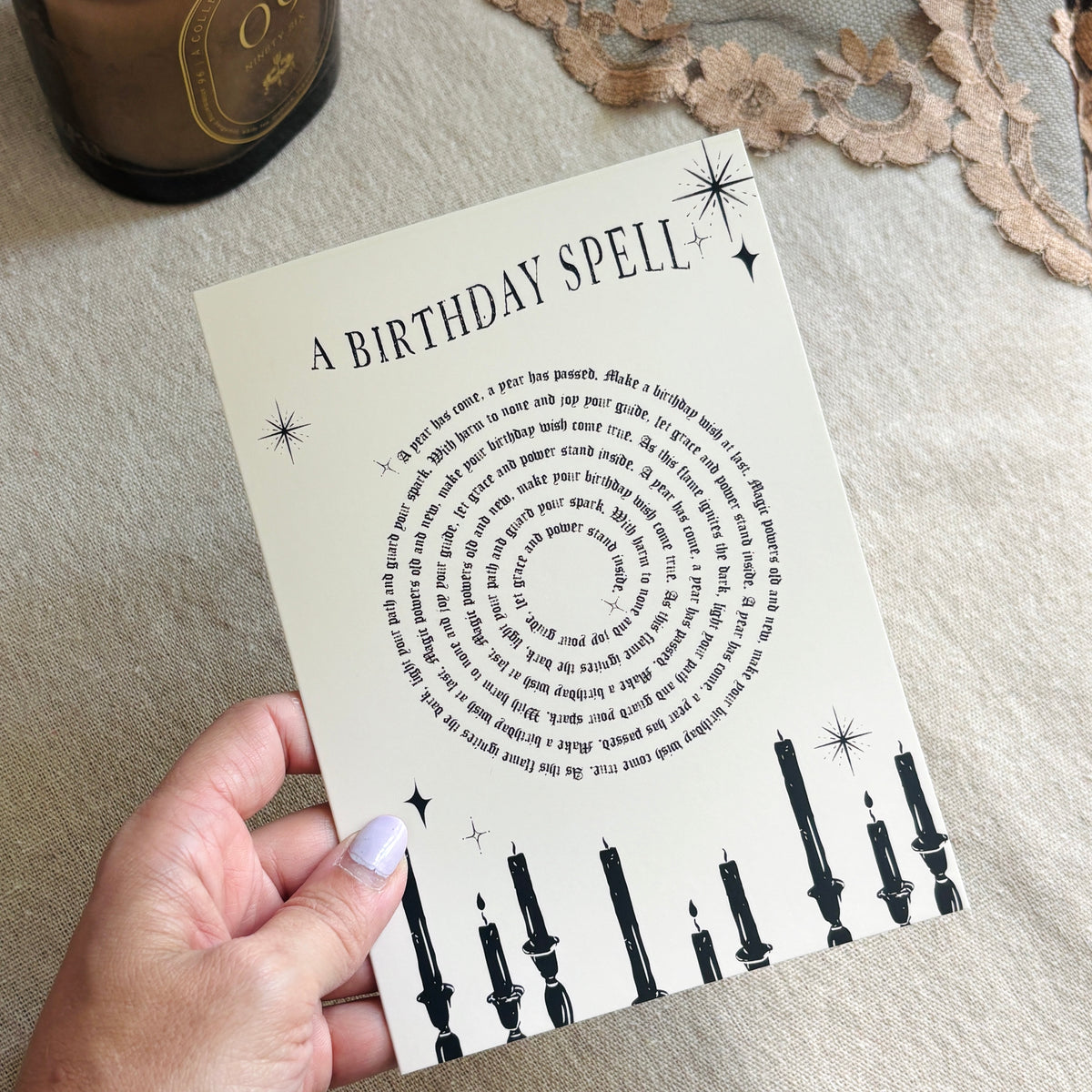 A greeting card that says "a birthday spell" with text for the spell in a spiral above black candles