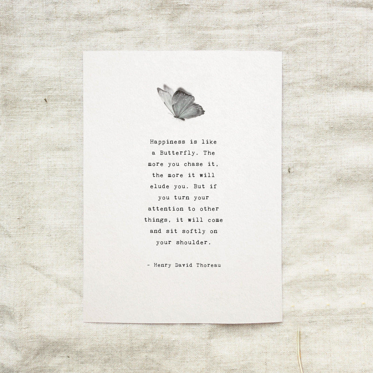 A minimalist art print featuring a black and white butterfly illustration above a typewriter-style quote by Henry David Thoreau. "Happiness is like a butterfly...