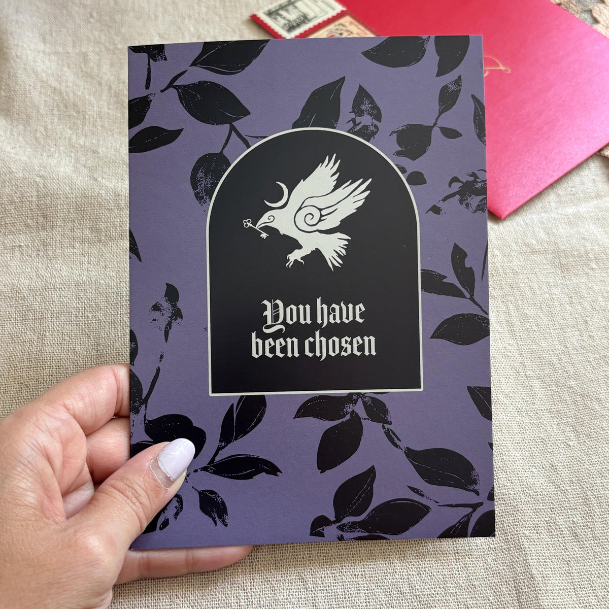 A black and purple patterned greeting card with an illustration of a crow and the text "You have been chosen"