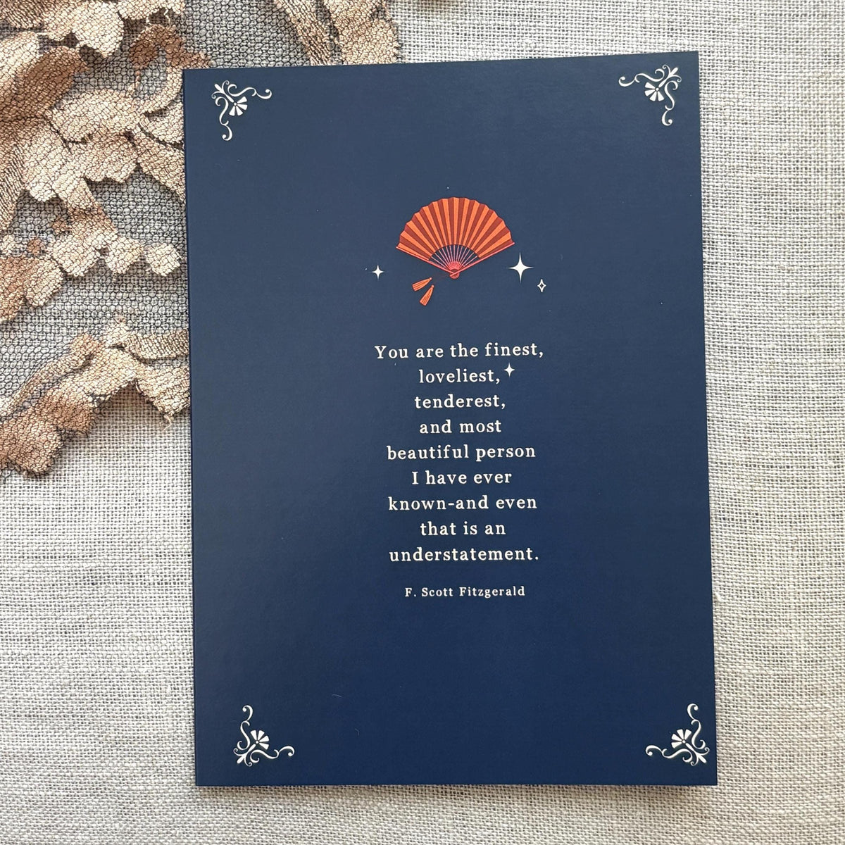 A navy blue greeting card featuring a quote by F. Scott Fitzgerald which says "you are the finest, loveliest, tenderest, and most beautiful person I have ever known-and even that is an understatement"