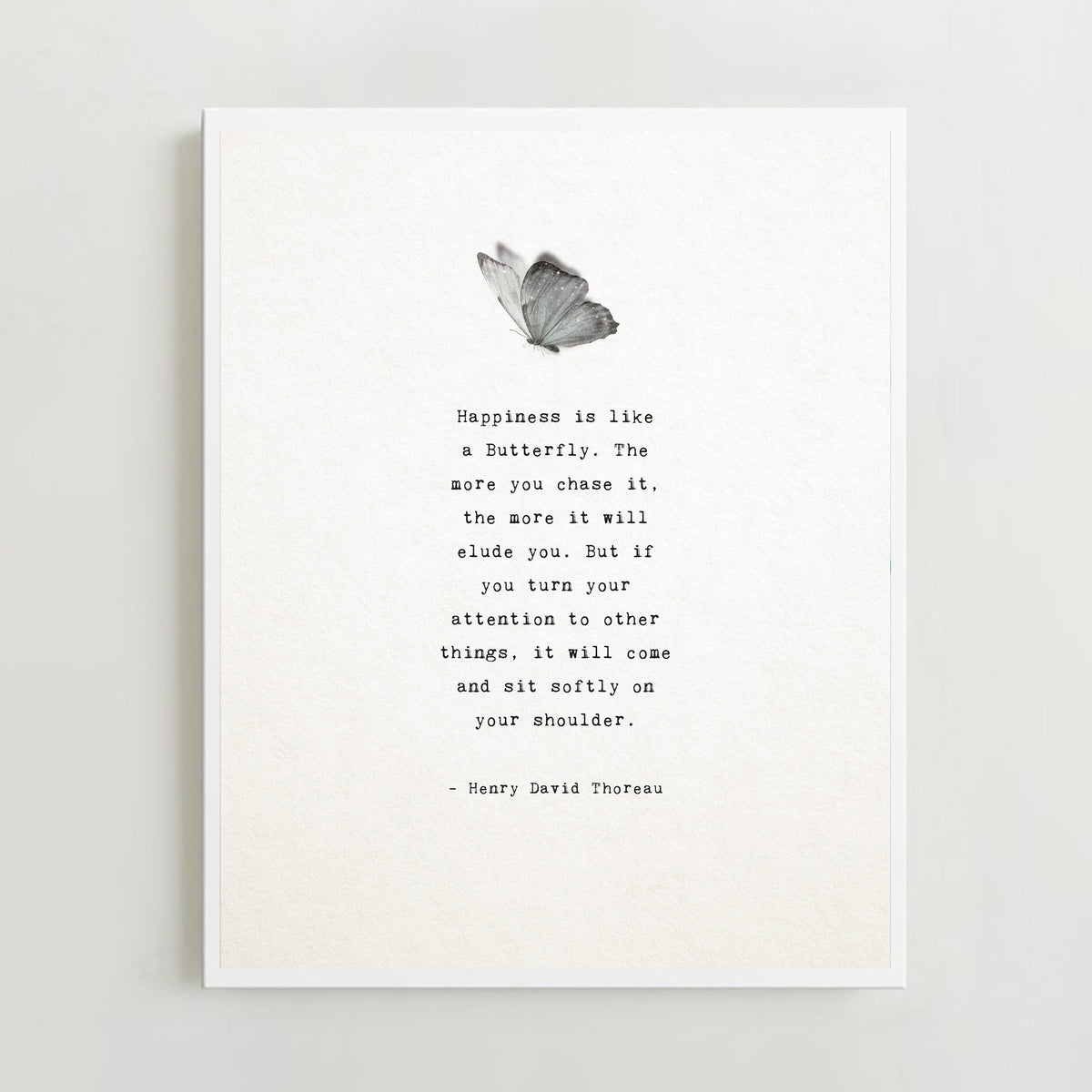 A minimalist art print featuring a black and white butterfly illustration above a typewriter-style quote by Henry David Thoreau. "Happiness is like a butterfly...
