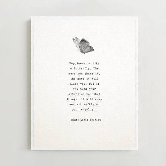 A minimalist art print featuring a black and white butterfly illustration above a typewriter-style quote by Henry David Thoreau. "Happiness is like a butterfly...