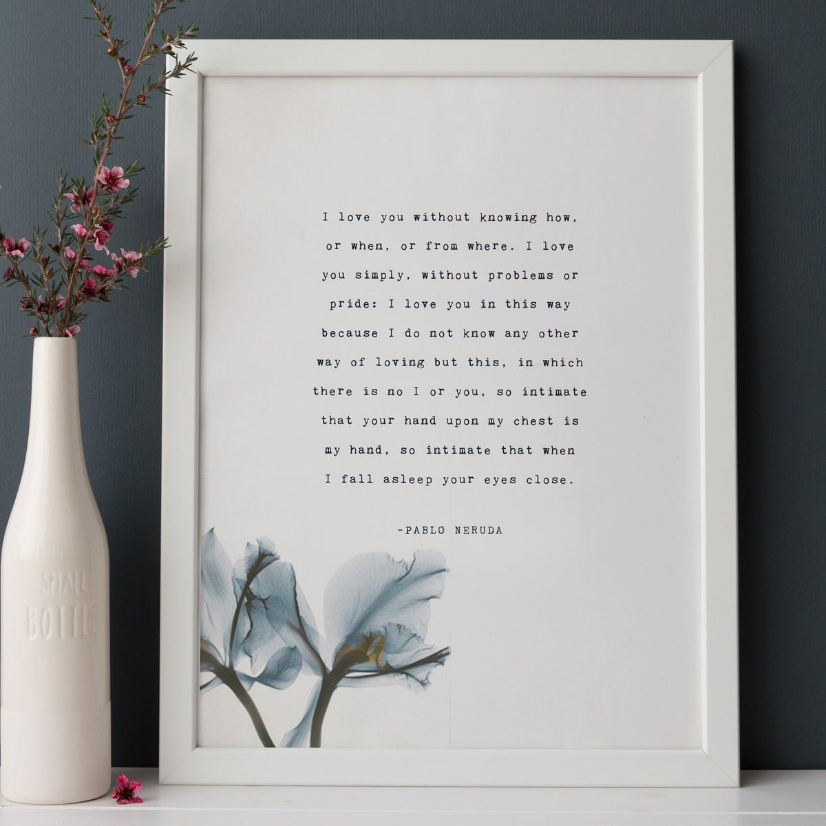 A vertical white art print featuring a quote by Pablo Neruda "I love you without knowing how, or when, or from where." in typewriter font and a blue watercolor floral illustration at the bottom. 