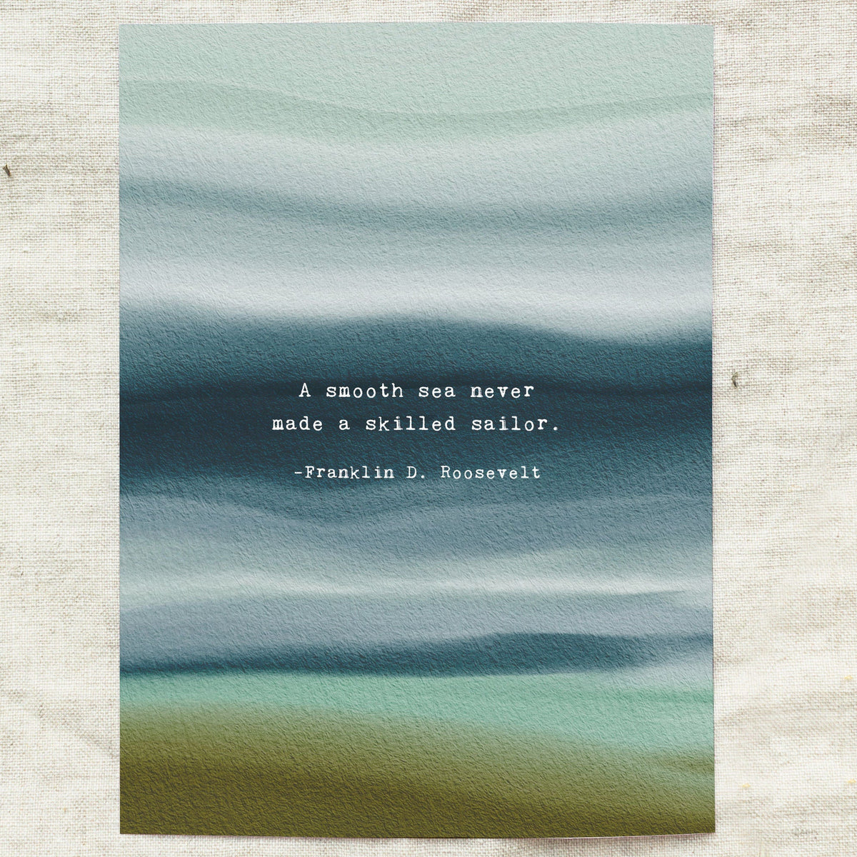 A vertical art print featuring an abstract watercolor seascape in muted teal, blue, and olive tones, with a white typewriter-style quote in the center reading, 'A smooth sea never made a skilled sailor. -Franklin D.