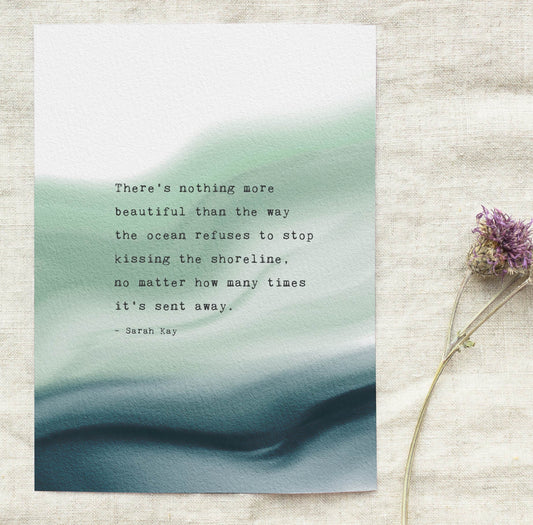 A vertical art print featuring a quote by Sarah Ray over an abstract watercolor background of soft green and deep teal. The quote says "there's nothing more beautiful than the way the ocean refuses to stop kissing the shoreline, no matter how many times it's sent away"