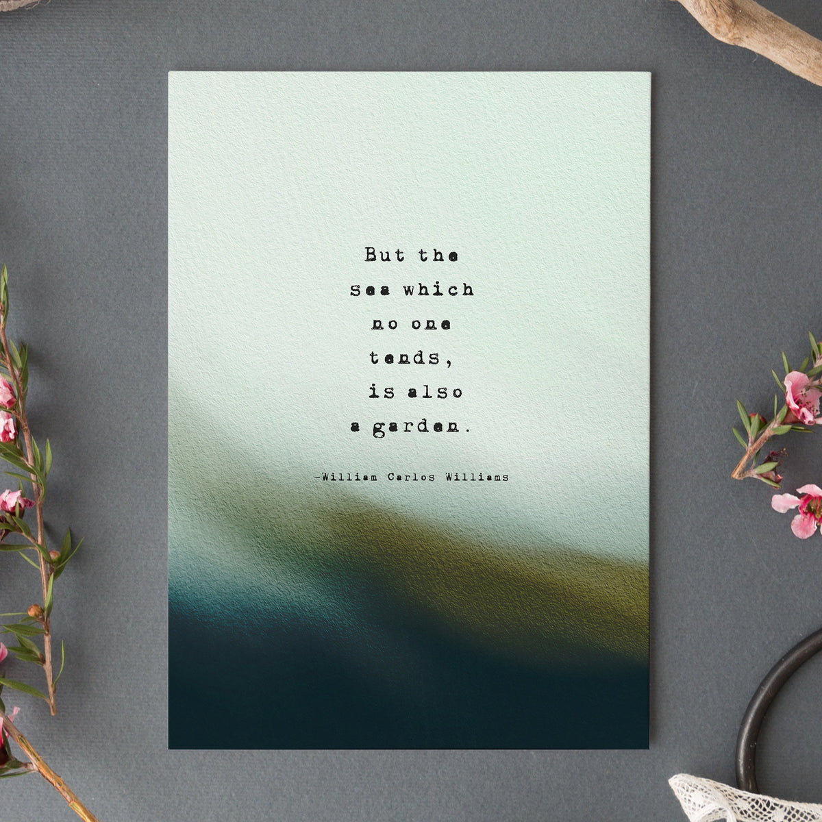A vertical art print featuring a quote by William Carlos Williams, 'But the sea which no one tends, is also a garden.' The print has a textured light blue and teal top half fading into a dark teal and olive bottom half