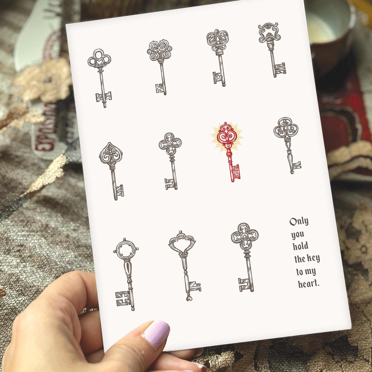 A white greeting card featuring illustrated vintage keys, with one red key in the center and the printed phrase 'Only you hold the key to my heart.' 