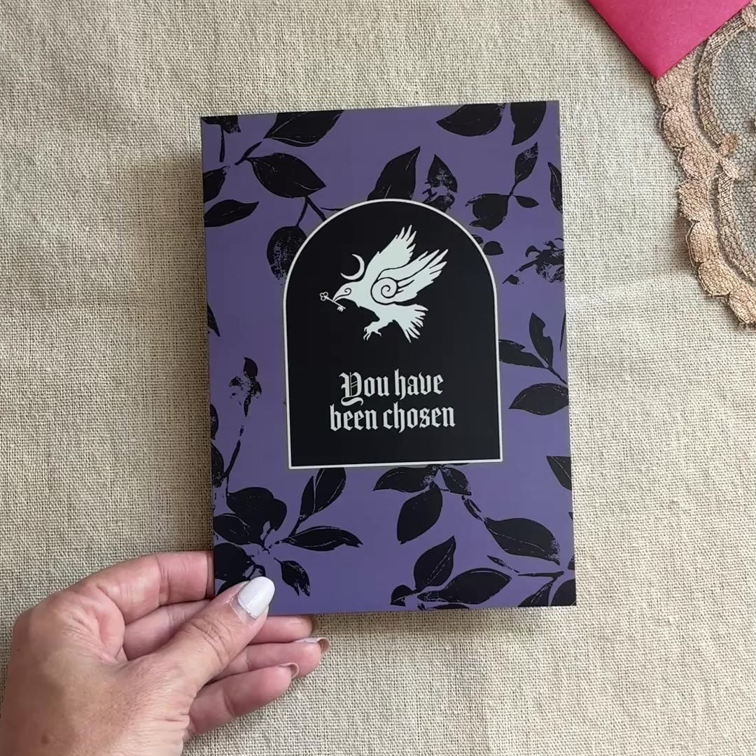 A black and purple patterned greeting card with an illustration of a crow and the text "You have been chosen"