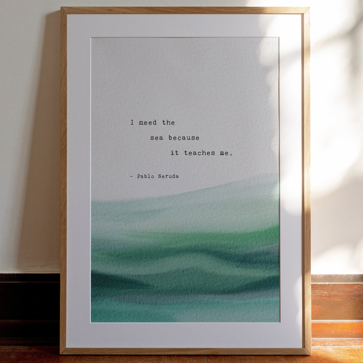 A typographic art print featuring a quote by Pablo Neruda over a watercolor ocean wave design in shades of teal. It says "I need the sea because it teaches me"